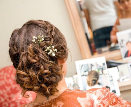 Recogido trenzado con detalle floral para pelo rizado para novias en Valladolid